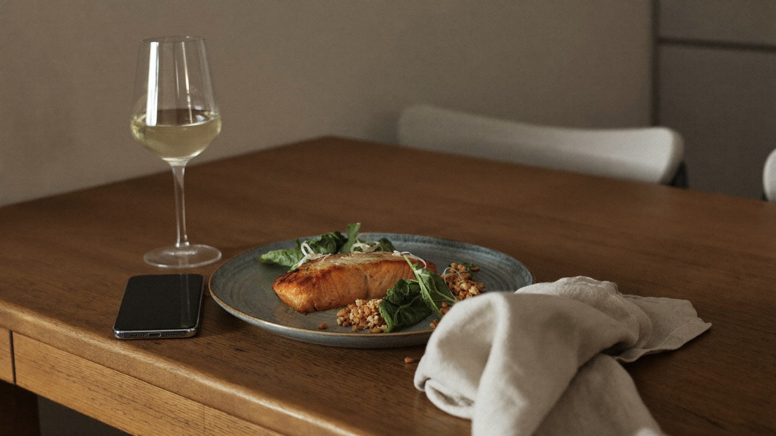 A simple home-cooked salmon dinner on the table with a phone set face-down beside it